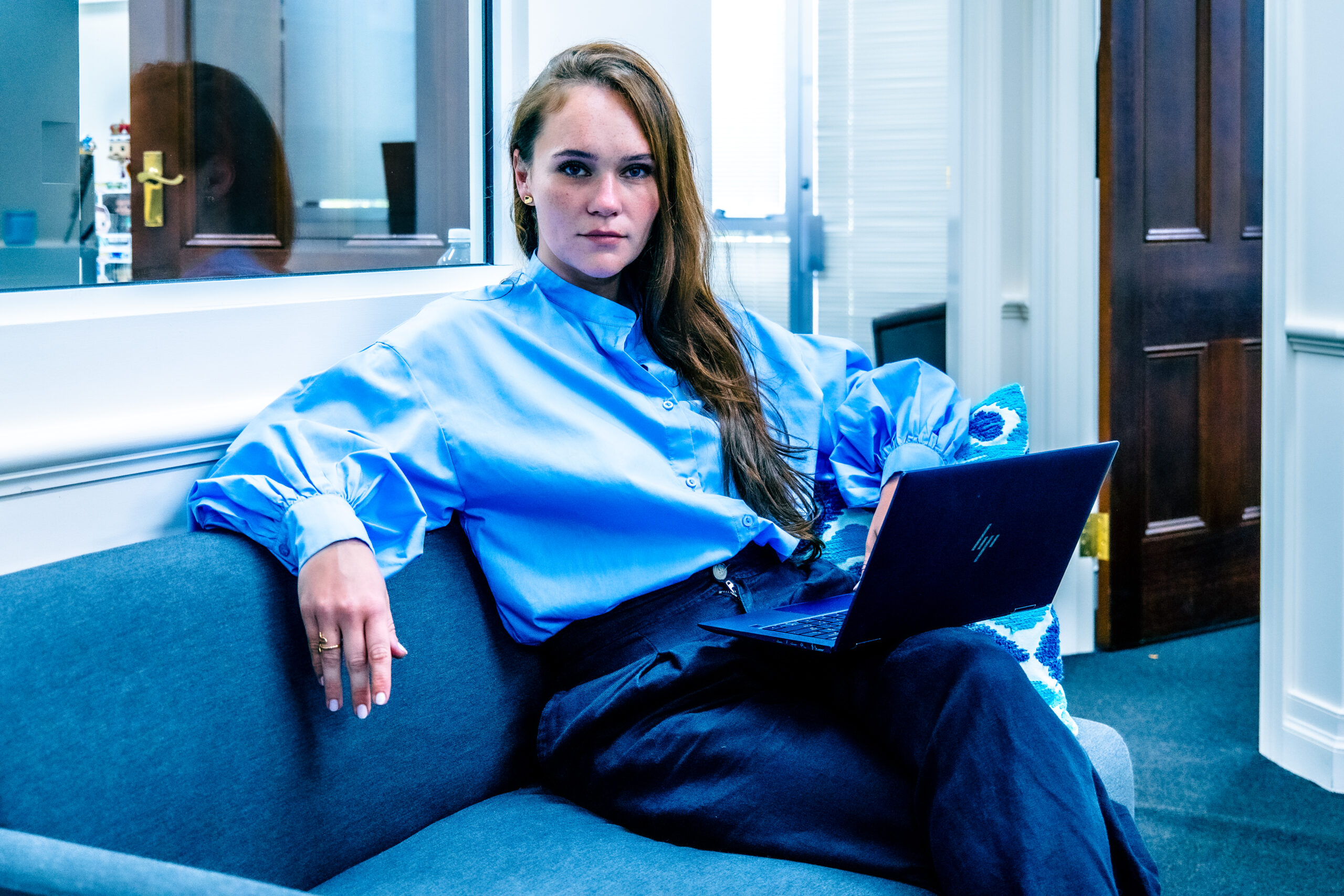 Portrait of Olga Burtseva seated on a sofa, laptop in hand—introducing her journey from accounting to cybersecurity leadership.